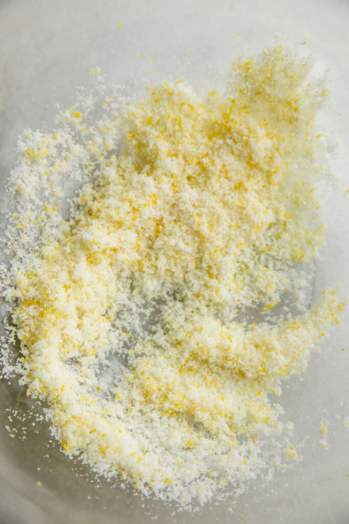 Rubbing the white sugar and lemon zest together in a bowl.