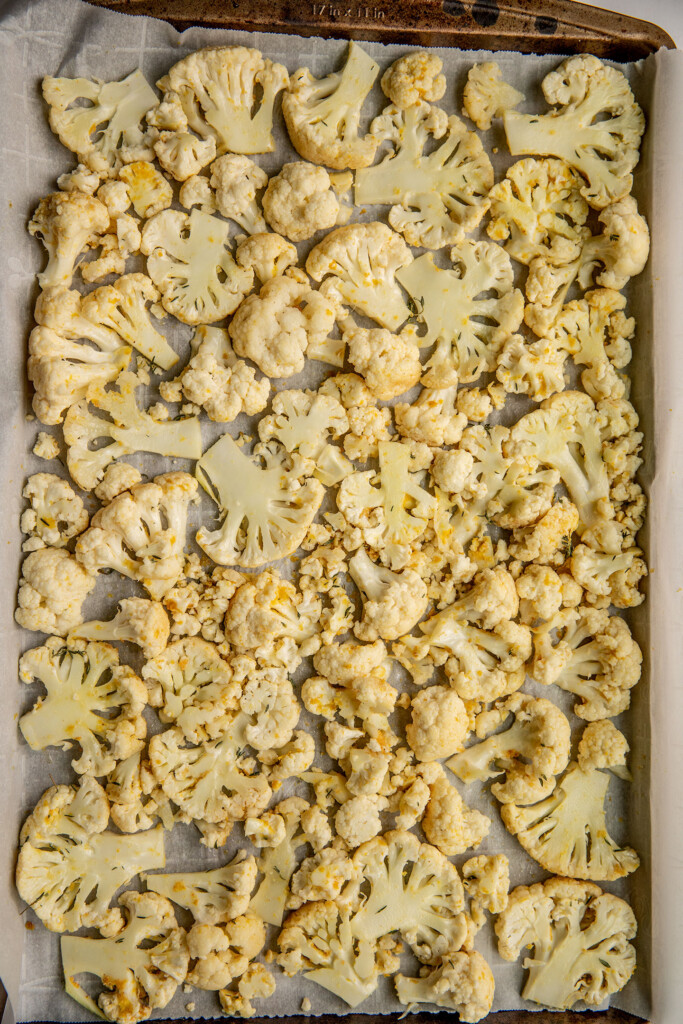 Seasoned cauliflower spread out on a baking tray.