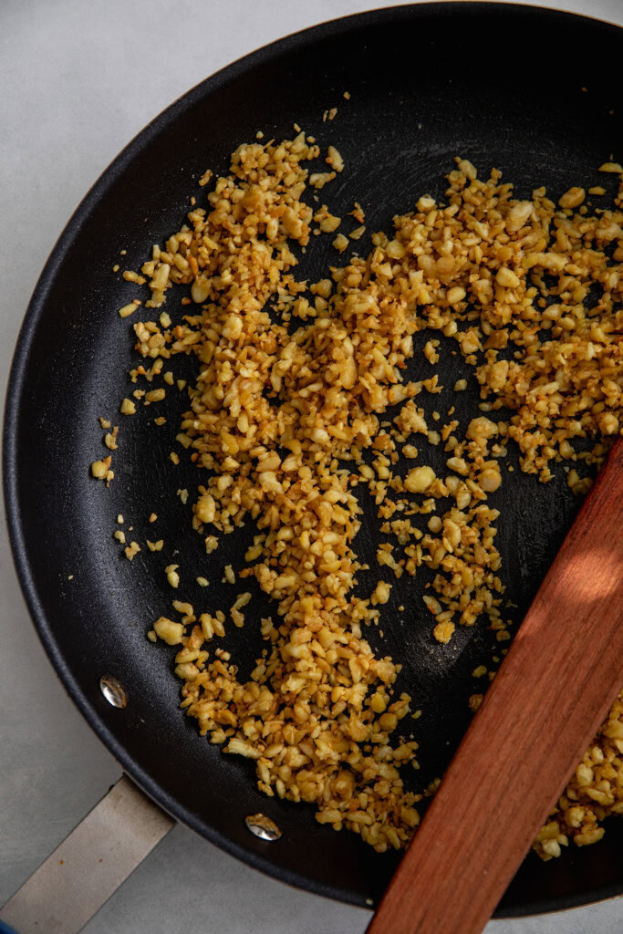 Sauteing the shredded tempeh until golden in color in a pan.