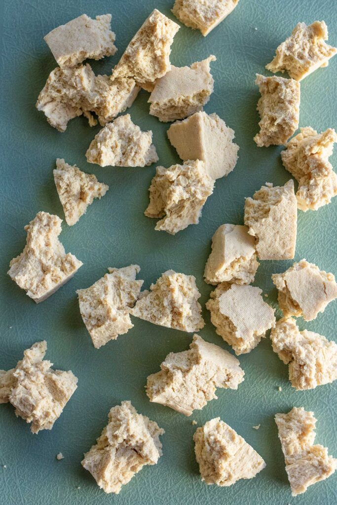 Torn frozen tofu chunks on a cutting board.