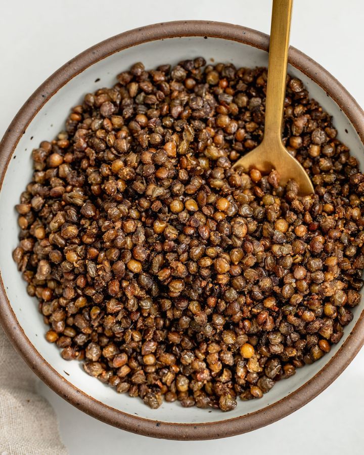 Bowl of crispy roasted lentils with a spoon tucked into them.